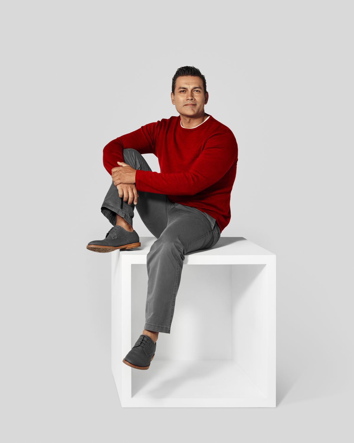 Man in red sweater sitting on top a white box